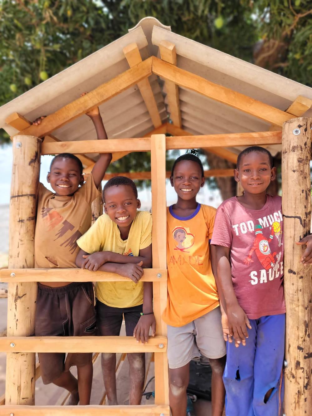 Crianças sorrindo em uma casinha de madeira, na África