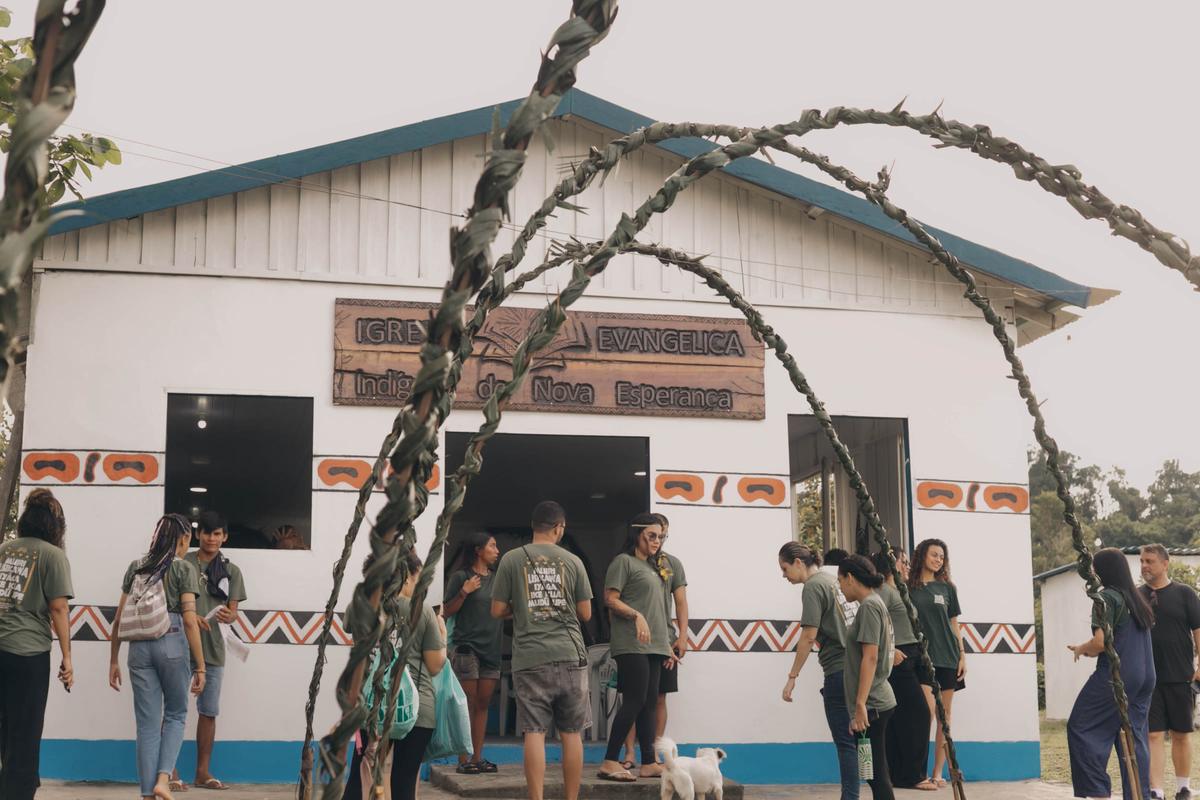 Igreja Evangélica Indígena de Nova Esperança, na Amazônia, com a equipe reunida à porta