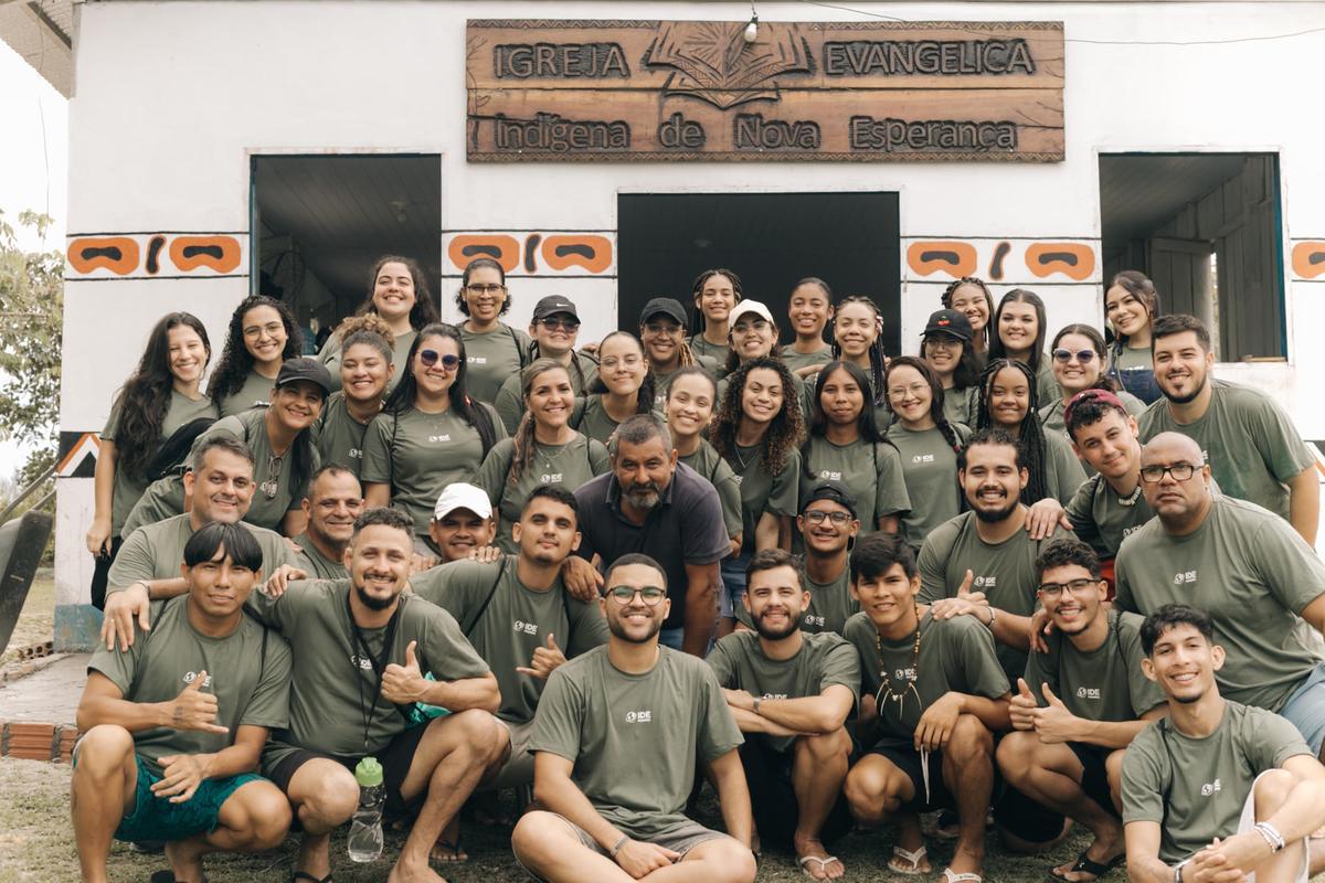 Equipe de voluntários sorrindo diante da Igreja Evangélica Indígena de Nova Esperança, na Amazônia