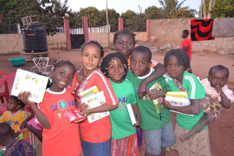 Crianças sorrindo com Bíblias infantis nas mãos, em Moçambique