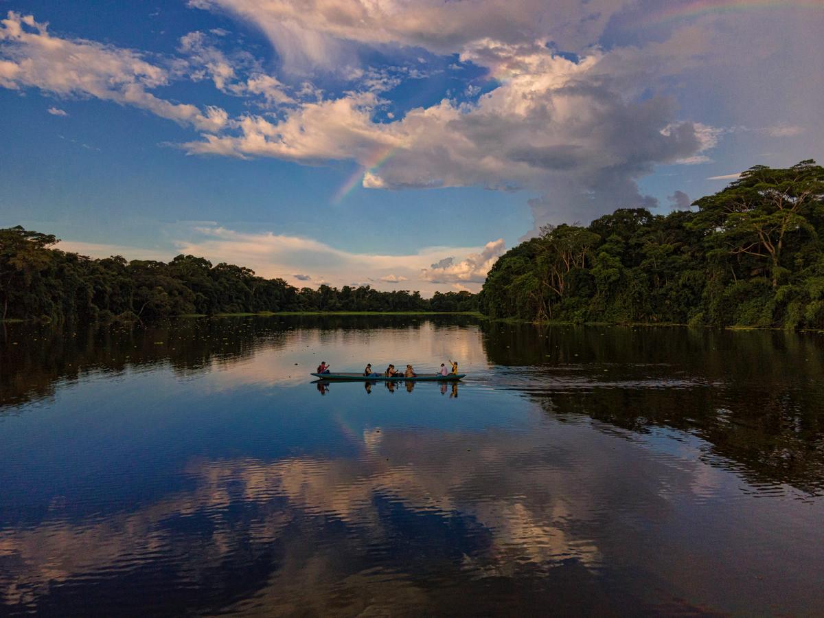 Canoa com missionários atravessando um rio da Amazônia ao entardecer